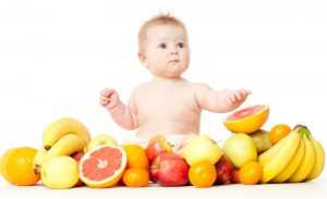The babe in an environment of the fresh fruit, isolated on the white