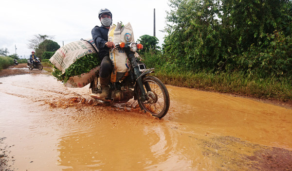 Người dân vận chuyển chè tươi qua “ao” nước trên đường dẫn vào Tổ dân phố 5, thị trấn Lộc Thắng.