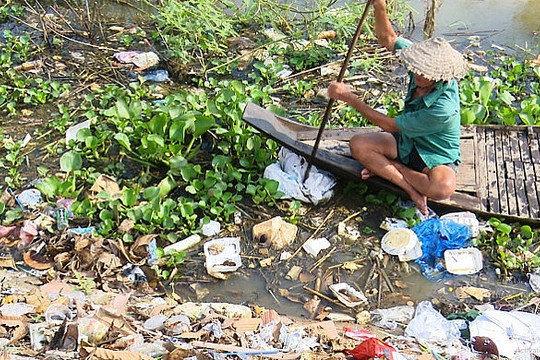 Lão nông bơi xuồng vớt rác thải nhựa mùa lũ